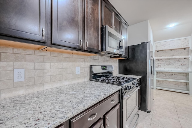 kitchen with appliances with stainless steel finishes, dark brown cabinets, light tile patterned floors, and backsplash