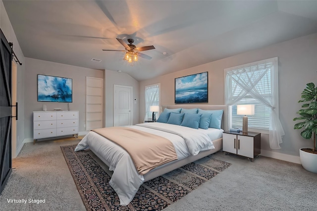 bedroom with light carpet, vaulted ceiling, a barn door, and ceiling fan