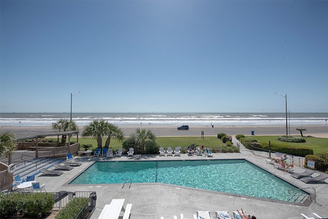 view of pool with a water view, a beach view, and a patio area