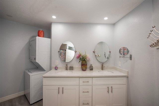 bathroom with vanity, stacked washer and clothes dryer, and hardwood / wood-style floors