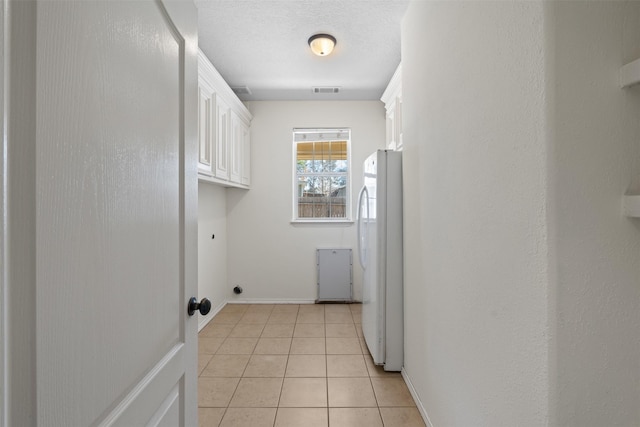 laundry area featuring cabinets, light tile patterned flooring, and a textured ceiling