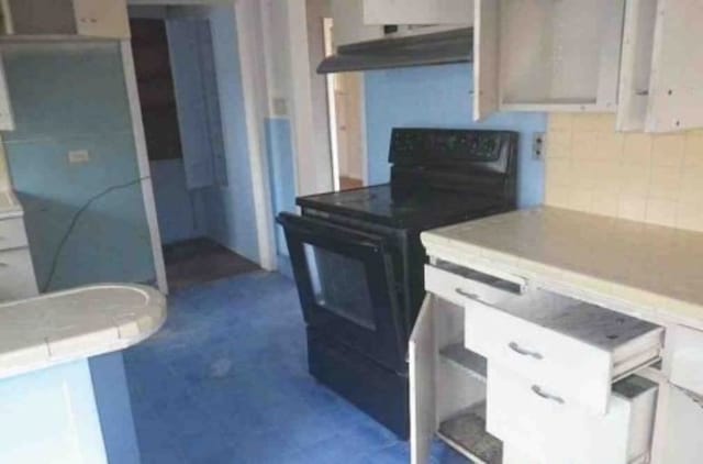 kitchen featuring black / electric stove, white cabinets, and backsplash