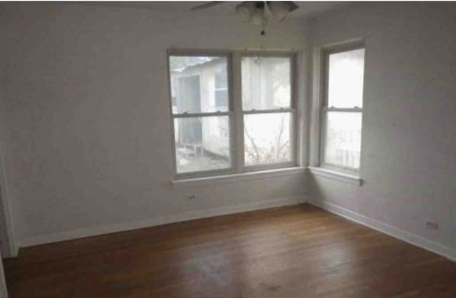 empty room with ceiling fan and dark hardwood / wood-style flooring