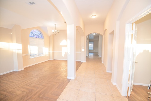 interior space with an inviting chandelier, baseboards, visible vents, and arched walkways