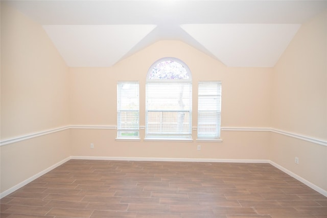 spare room with vaulted ceiling, wood finished floors, and baseboards