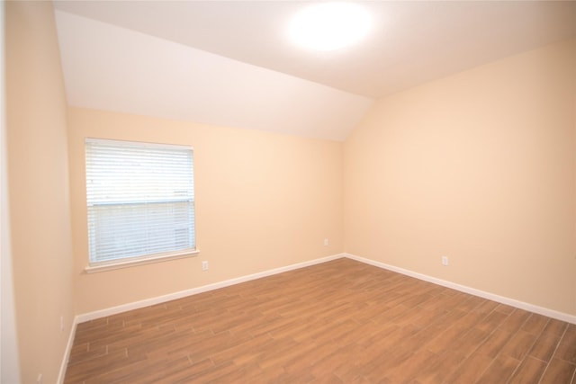 unfurnished room featuring vaulted ceiling, baseboards, and wood finished floors