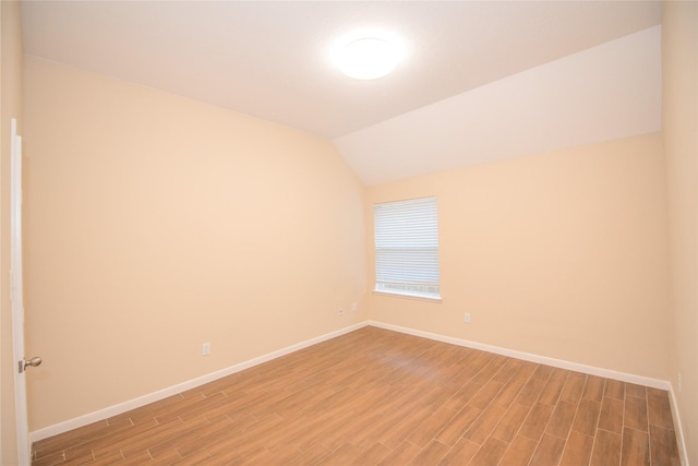 unfurnished room featuring lofted ceiling, light wood finished floors, and baseboards