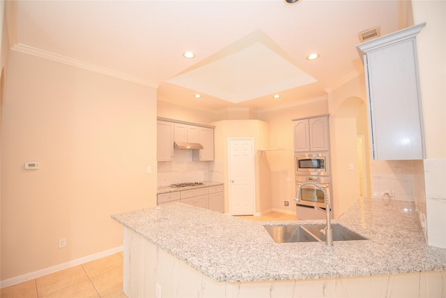 kitchen featuring a peninsula, a sink, visible vents, backsplash, and stainless steel microwave