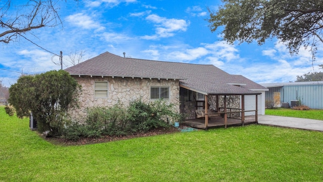 rear view of property featuring cooling unit, a garage, and a lawn