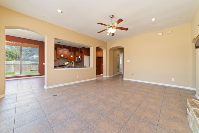 unfurnished living room with light tile patterned flooring, ceiling fan, and sink