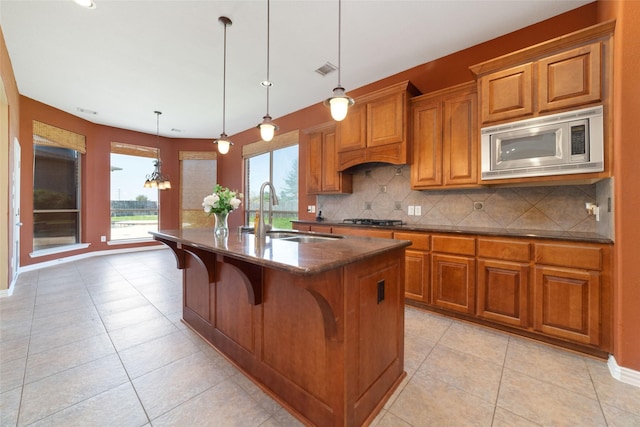 kitchen with sink, hanging light fixtures, stainless steel appliances, a kitchen breakfast bar, and a center island with sink