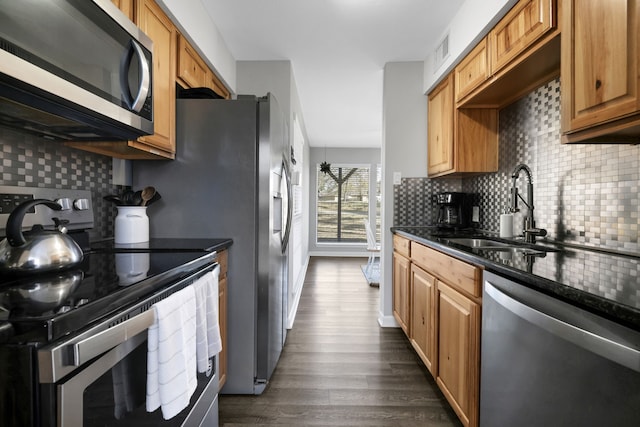 kitchen featuring sink, tasteful backsplash, dark stone countertops, appliances with stainless steel finishes, and dark hardwood / wood-style floors