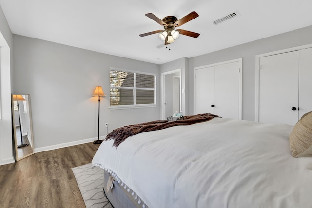 bedroom with multiple closets, ceiling fan, and dark hardwood / wood-style flooring