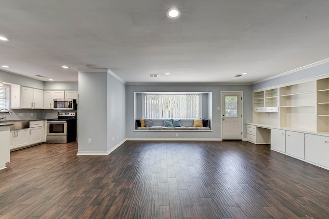 unfurnished living room featuring plenty of natural light, built in desk, and dark hardwood / wood-style flooring