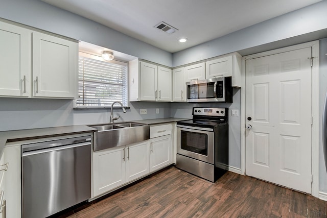 kitchen featuring appliances with stainless steel finishes, dark hardwood / wood-style flooring, sink, and white cabinets