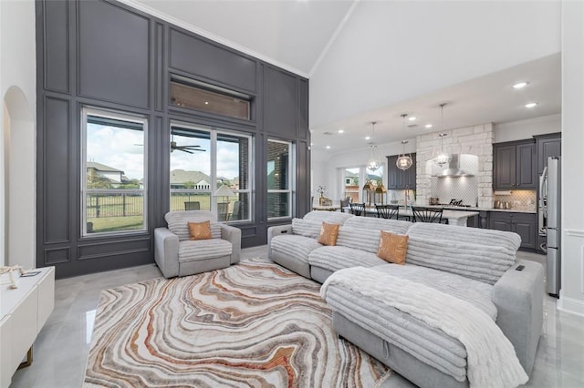 living room with ornamental molding and high vaulted ceiling