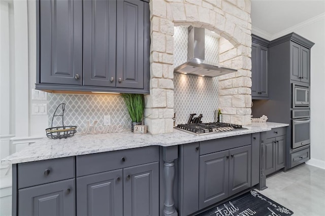 kitchen featuring stainless steel appliances, ornamental molding, gray cabinetry, and wall chimney range hood