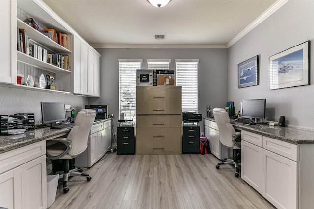 office space with built in desk, ornamental molding, and light wood-type flooring