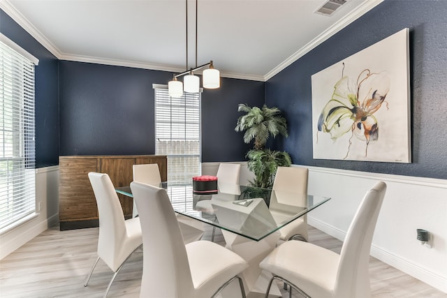 dining space with crown molding, a wealth of natural light, and light wood-type flooring