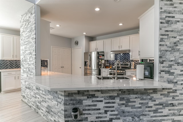 kitchen with white cabinetry, appliances with stainless steel finishes, kitchen peninsula, and decorative backsplash