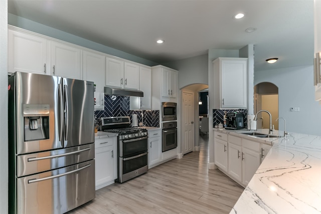 kitchen with appliances with stainless steel finishes, sink, white cabinets, and light stone counters