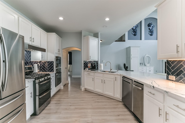 kitchen featuring white cabinetry, stainless steel appliances, light stone countertops, and sink