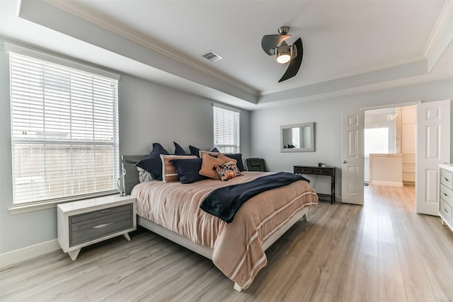 bedroom featuring a tray ceiling, crown molding, ceiling fan, and light wood-type flooring