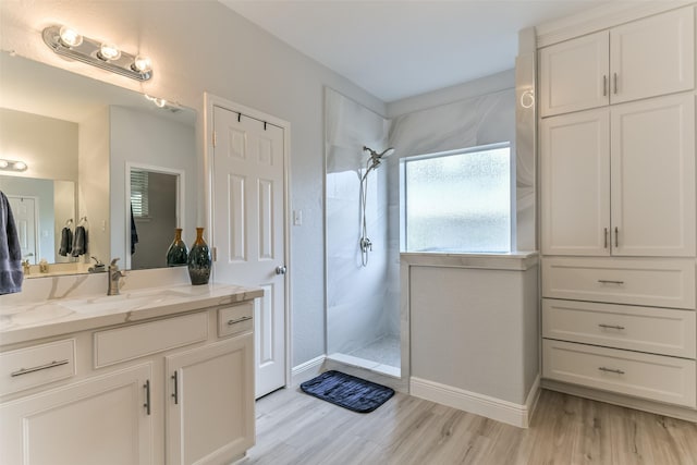 bathroom featuring hardwood / wood-style flooring, vanity, and tiled shower