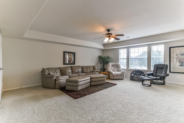 carpeted living room featuring ceiling fan and a tray ceiling