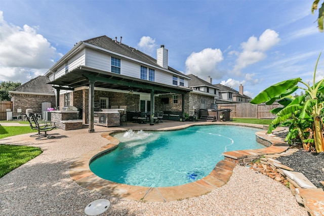 view of swimming pool featuring pool water feature, area for grilling, a grill, and a patio area