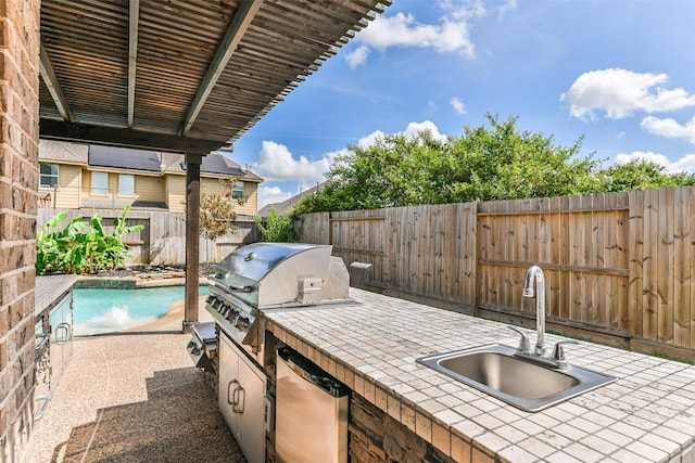 view of patio featuring a fenced in pool, a grill, an outdoor kitchen, and sink