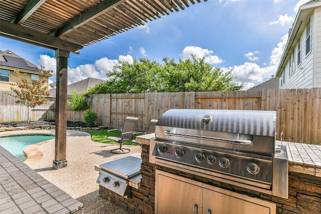 view of patio / terrace featuring a fenced in pool, area for grilling, and exterior kitchen