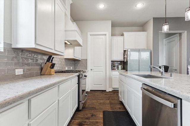 kitchen with stainless steel appliances, light stone countertops, sink, and white cabinets