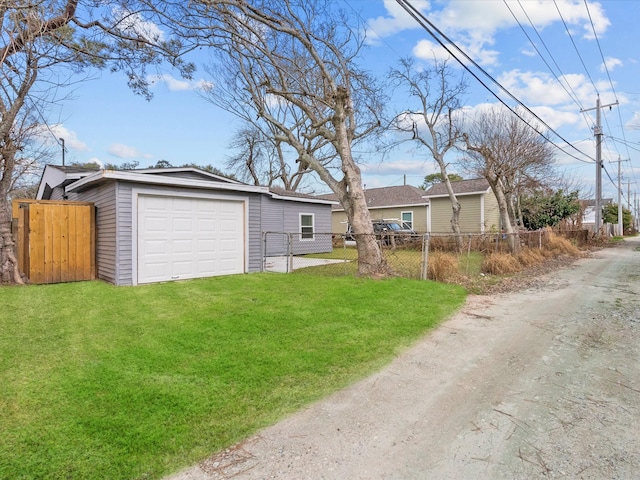 detached garage featuring a gate, fence, and driveway