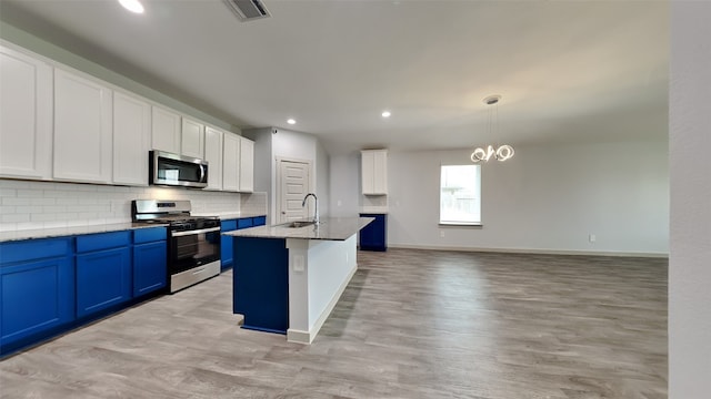 kitchen featuring pendant lighting, a center island with sink, stainless steel appliances, light stone counters, and blue cabinets