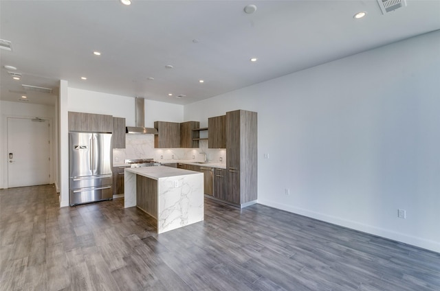 kitchen with sink, a center island, stainless steel fridge, wall chimney range hood, and backsplash