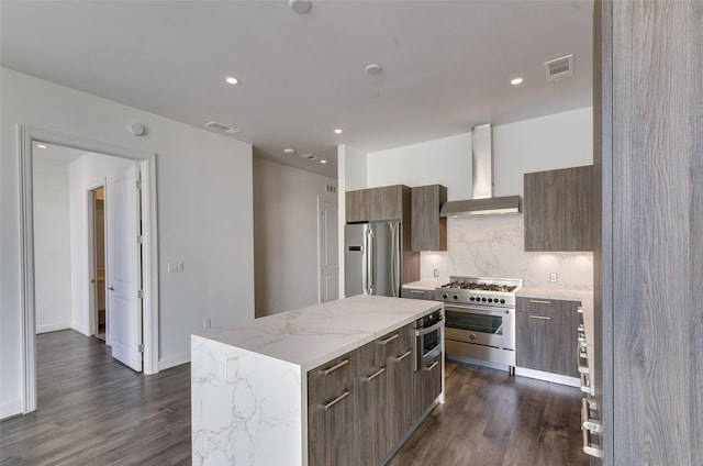 kitchen with dark hardwood / wood-style floors, tasteful backsplash, a center island, stainless steel appliances, and wall chimney range hood