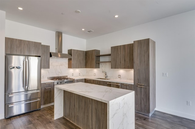 kitchen featuring sink, a center island, appliances with stainless steel finishes, wall chimney range hood, and backsplash