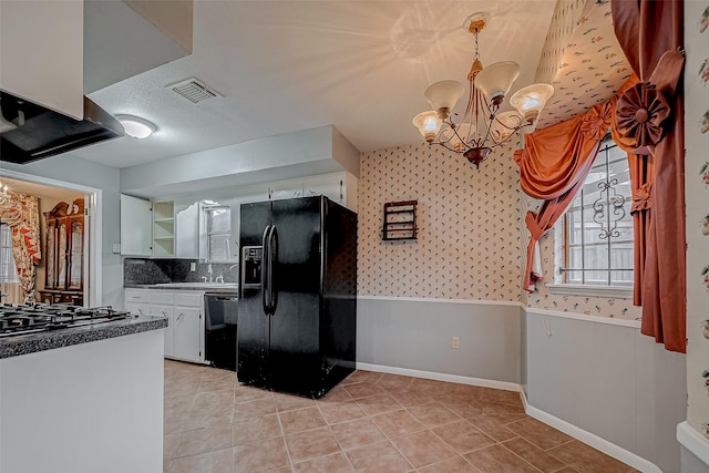 kitchen with an inviting chandelier, white cabinets, light tile patterned floors, and black appliances