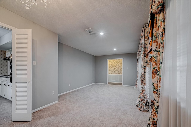 spare room featuring light colored carpet and a textured ceiling