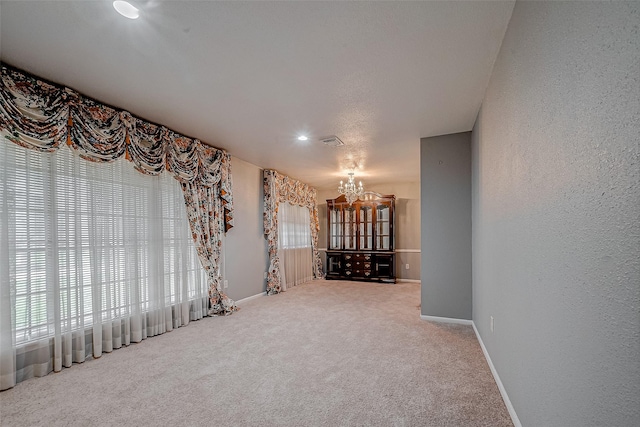 unfurnished room with carpet flooring and a chandelier