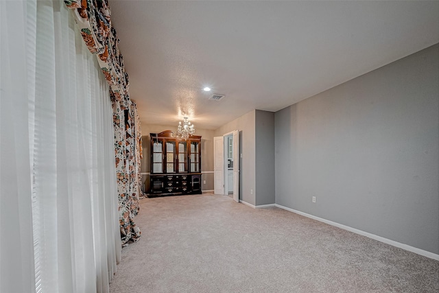 empty room with carpet flooring and a chandelier