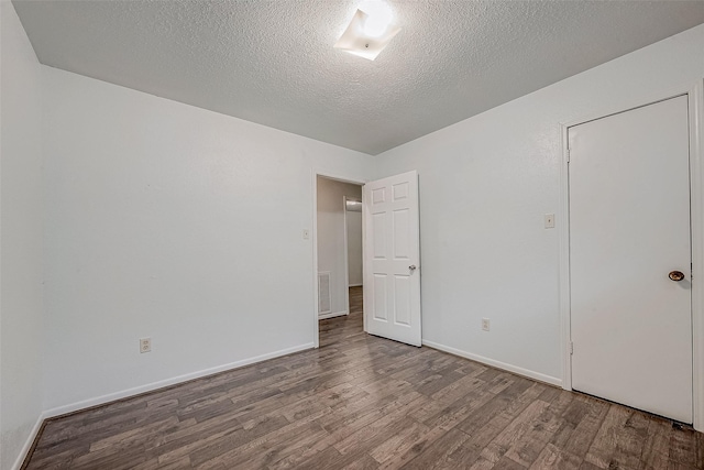 spare room featuring wood-type flooring and a textured ceiling