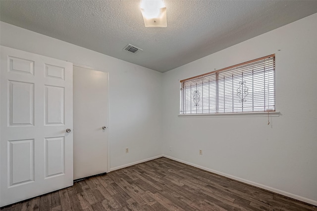 unfurnished bedroom with a textured ceiling and dark hardwood / wood-style flooring