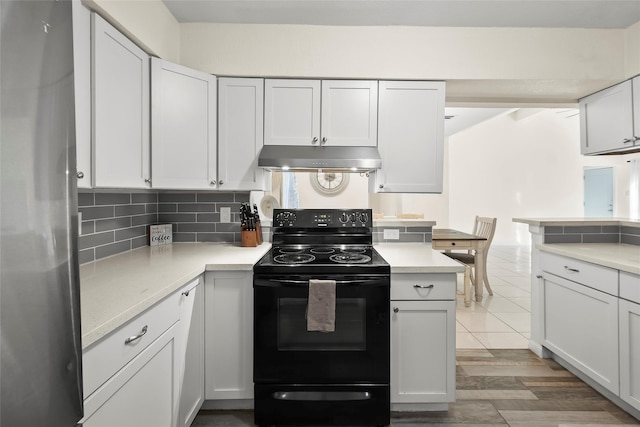 kitchen featuring white cabinetry, black / electric stove, decorative backsplash, and stainless steel fridge