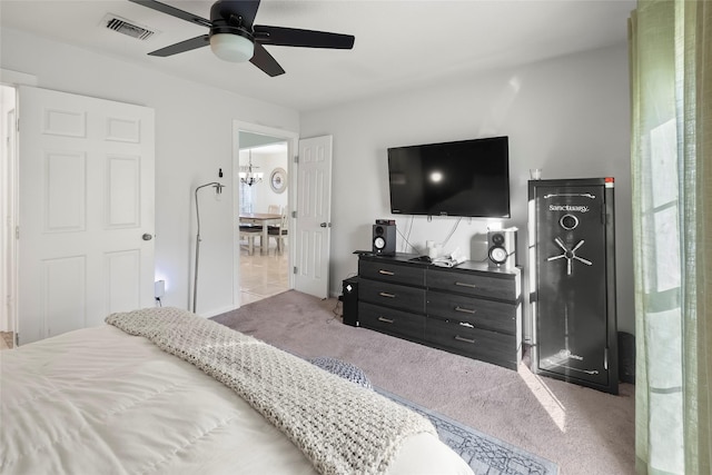 carpeted bedroom featuring ceiling fan with notable chandelier