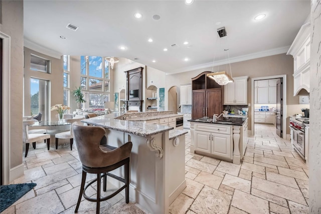 kitchen featuring a large island with sink, double oven range, a kitchen breakfast bar, and decorative light fixtures