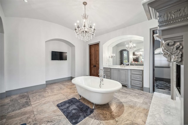 bathroom with an inviting chandelier, lofted ceiling, vanity, and a washtub