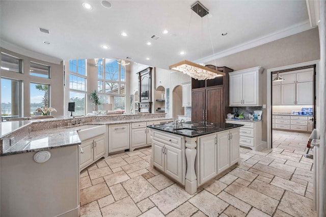 kitchen featuring white cabinetry, decorative light fixtures, dark stone countertops, and a spacious island