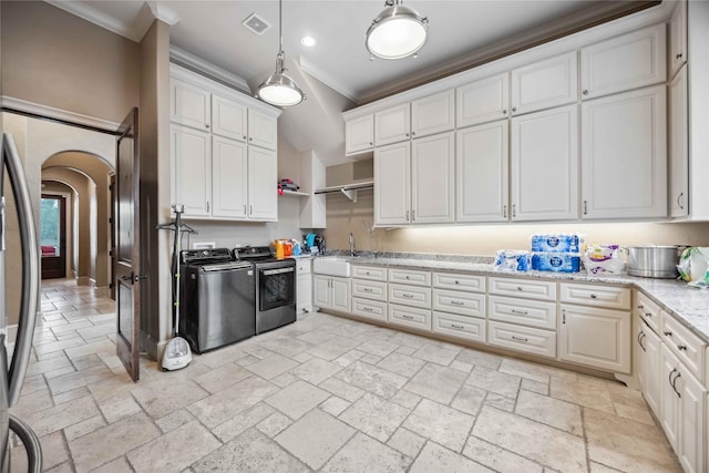 kitchen featuring crown molding, stainless steel refrigerator, white cabinetry, light stone counters, and washer and dryer